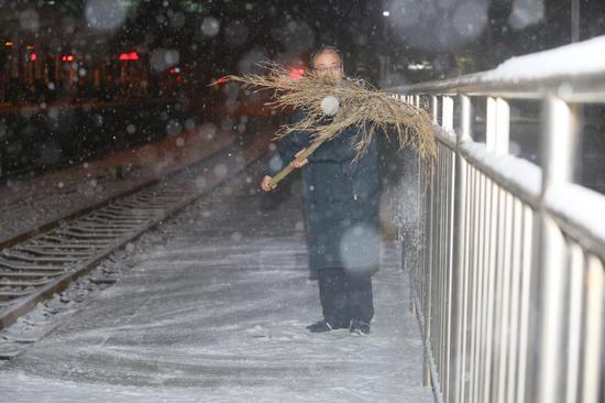 新乡车务段新乡车站工作人员在清扫安全围栏处积雪。（王振兴 摄）