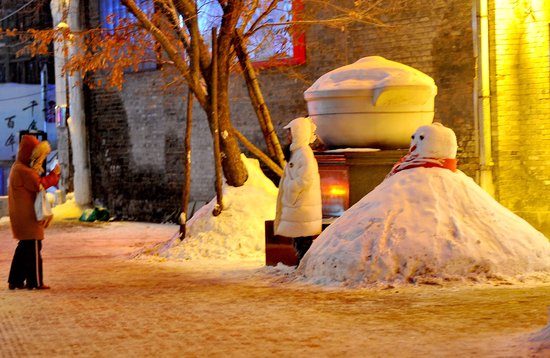  一家老字号饭店门口堆起了大雪人，吸引游客拍照