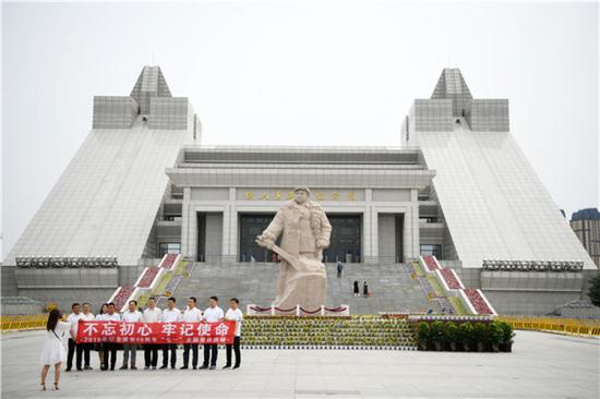 人们在铁人王进喜纪念馆前手举写有“不忘初心，牢记使命”的条幅合影留念（6月25日摄）。新华社记者 王建威 摄