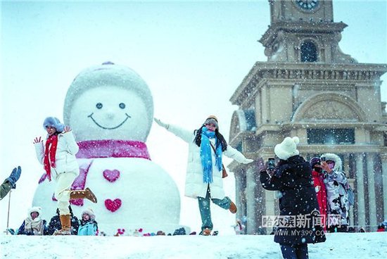  在哈尔滨音乐公园，游客与大雪人雪中“共舞”。