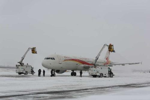 机场工作人员为飞机清理冰雪。仇建摄