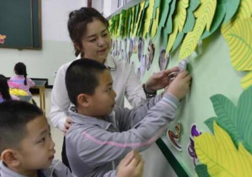资料图：学生在老师的指导下将自己的照片贴上笑脸墙。中新社记者 刘新 摄