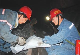 刘金奇（右）在井下工作面对照图纸研究技术方案。 王东摄