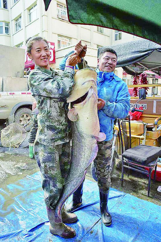 渔民董旗和妻子拿着鲇鱼。照片由虎林市委宣传部提供