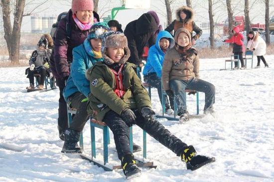 孩子们尽情的在冰上玩着爬犁