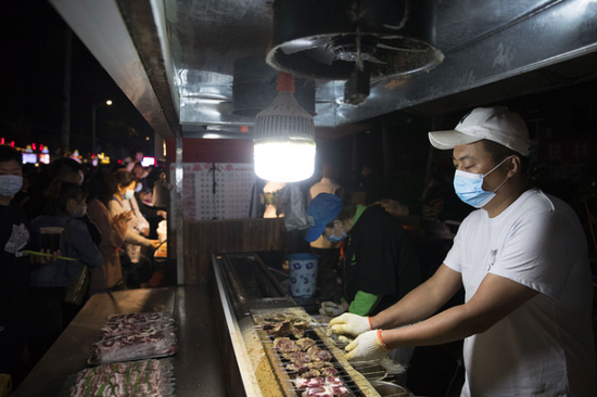 6月4日，商家在哈尔滨市“师大夜市”上制作美食。新华社发（张涛 摄）