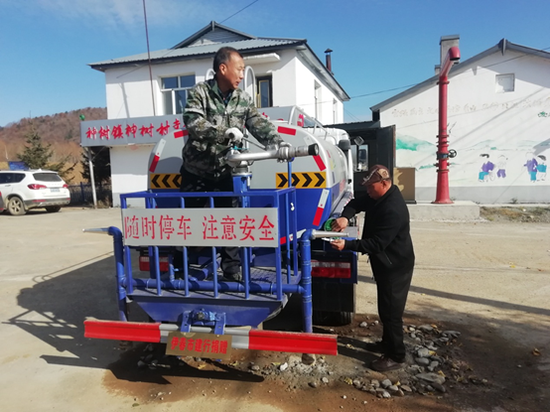 建设银行黑龙江伊春分行向神树村捐赠的洒水车（左为建行驻村干部李秀民）