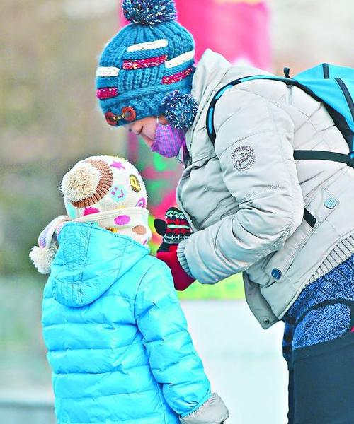 1月18日，一名在北京龙潭公园游玩的家长给孩子戴上手套。 新华社记者罗晓光摄