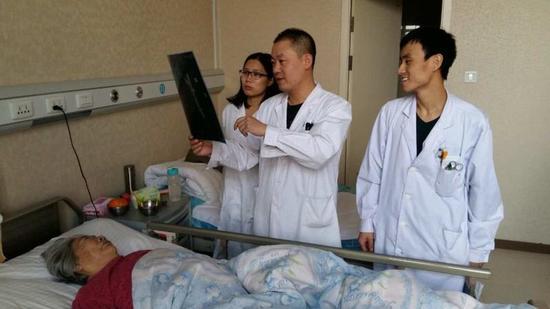 图为哈市五院骨科八病房医生赵德来(中)在查看高龄老人术后情况(田少
