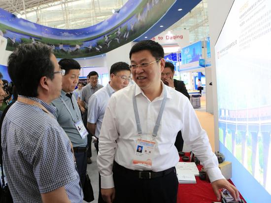第四届中国国际新材料产业博览会上齐齐哈尔市市长李玉刚（右一）向参展商了解产品性能。  张亮 摄