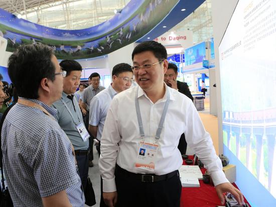 第四届中国国际新材料产业博览会上齐齐哈尔市市长李玉刚(右一)向参展商了解产品性能。 张亮 摄
