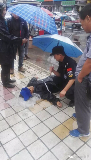 一名巡警则蹲在一倒地老人身旁为老人打伞