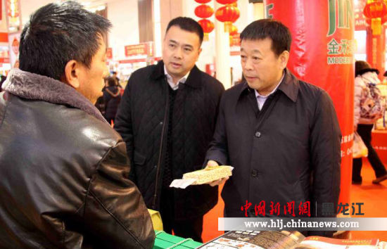 黑龙江省绿色食品发展中心主任李旭（左）陪同黑龙江省农委主任王金会在与参展企业交流，对接市场