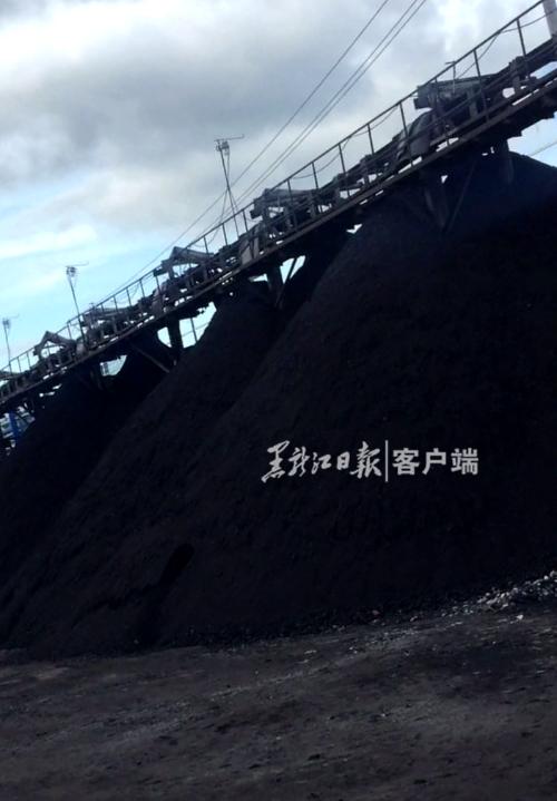 7月5日，记者进入鹤岗市东山区三街的泰源煤矿内暗访，煤矿厂院内煤溜子下面堆积成山的煤。煤矿厂一名工作人员与记者攀谈卖煤。