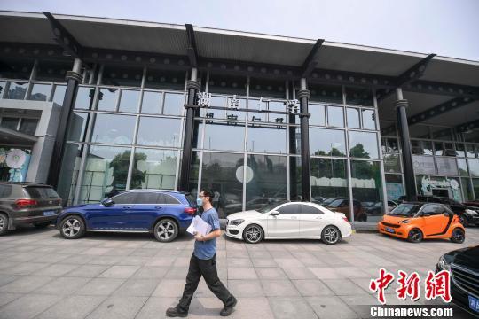 图为一人从奔驰4S店经过。 杨华峰 摄