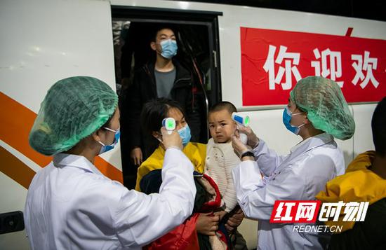 医务人员对下车旅客进行体温检测。