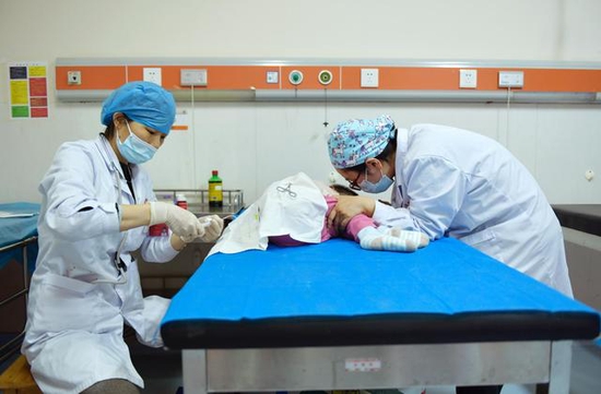 图片说明：湖南省儿童医院神经内科副主任医师康庆云（左）、主治医师刘舒蕾（右）给4岁6个月脊髓性肌肉萎缩症女孩乐乐（化名）进行诺西那生钠注射液注射治疗。姚家琦摄