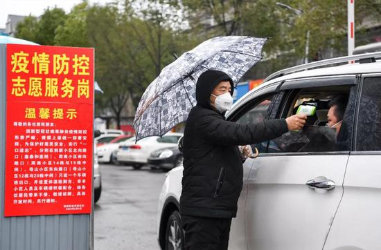 2月6日,长沙市开福区秀峰街道兴联母山小区,社区志愿者为进出居民测量体温。