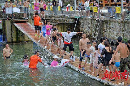 (8月19日,新邵县坪上镇清水村,当地村民和游客在“网红桥”上尽情玩耍。 湖南日报·华声在线记者 李健 摄)