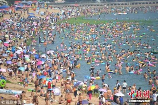 ↑7月29日,数千名游客在山东青岛第一海水浴场纳凉避暑。 王海滨 摄 图片来源:视觉中国