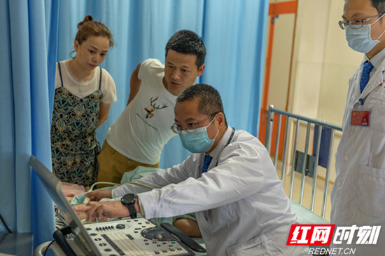 湖南省儿童医院心血管内科主任医师陈智正在给子毅做床旁彩超。