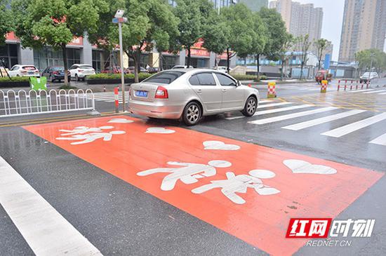  长沙市长郡双语实验中学正门前地面上的“爱心斑马线”十分醒目，长沙城区在部分学校周边路段推广实施“爱心斑马线”。