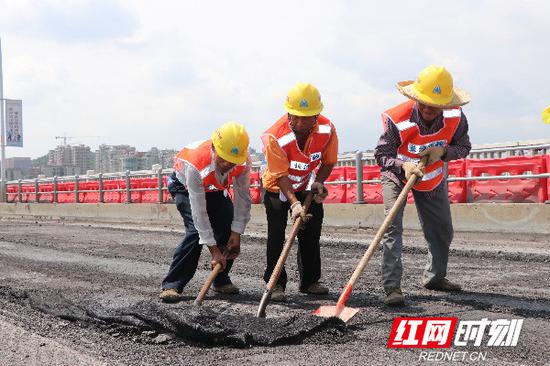 张师傅与他的两个工友卯足了劲，终于用铲子共同将沥青从路面上刮下来。