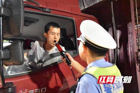 民警对过路货车司机进行酒驾测试。