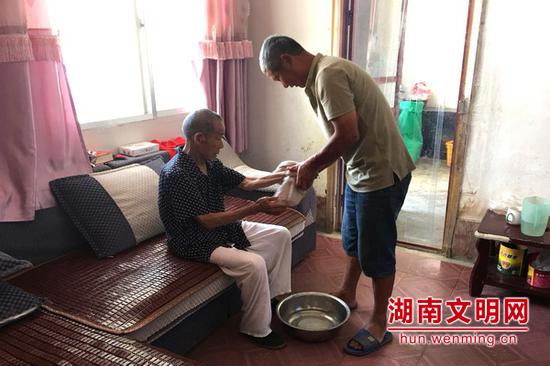 周仁南(右一)给已故妻子前夫的父亲擦手。图片来源:湖南文明网