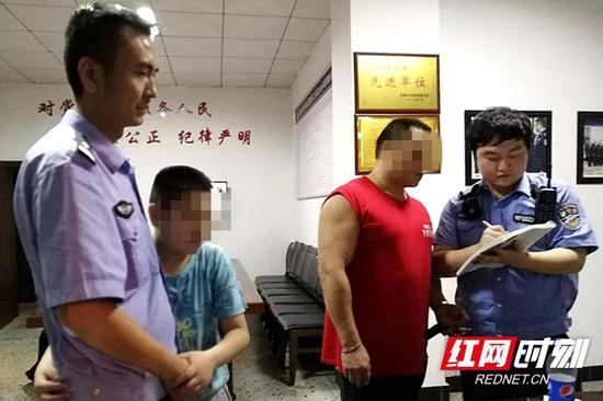 男孩父亲在《接处警登记本》上签字,男孩依靠在民警身边。