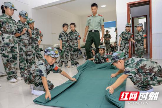 夏令营学员在教官的带领下学习了军被的折叠,并分组进行了竞赛。