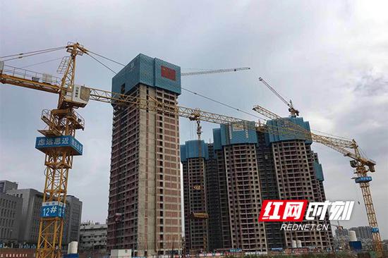 项目工地高高挂起红旗,工地上的工人们,正利用施工黄金期,撸起袖子加油干。