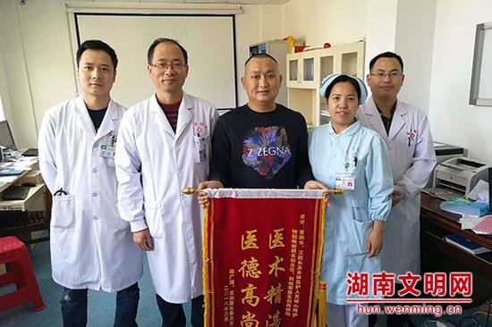 患者送来锦旗感谢胡军(右一)。图片来源:湖南文明网
