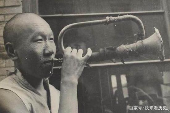 民国时期的一名磨刀匠,他正通过吹喇叭来招揽顾客。