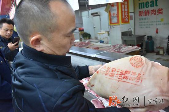执法人员查看猪肉的“两证两章”是否齐全。