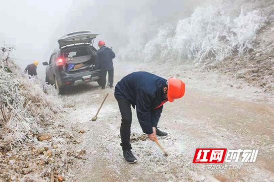 电力工人凿开山路冰层。