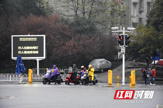 路口电子屏提示：行人过路请走斑马线，勿闯红灯。