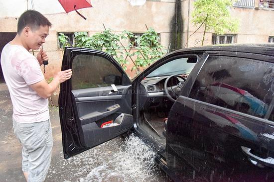 6月10日，桂阳县城一小区内，车主将车内积水放出。