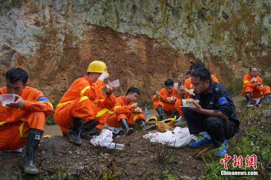 贵州水城县山体滑坡现场，救援人员雨中用餐。中新社记者 贺俊怡 摄