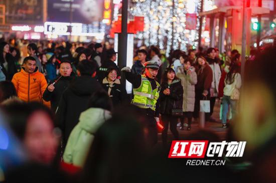 节假日里最辛苦的人，黄兴路上人行横道前，交警挥手示意行人过马路。