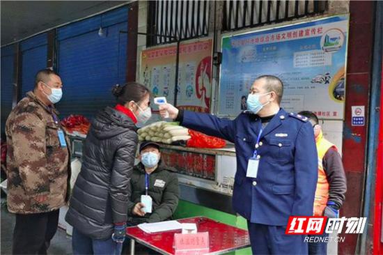 2月3日,张志云(前排右一)在岳阳平江县西街菜市场为经营户测量体温。