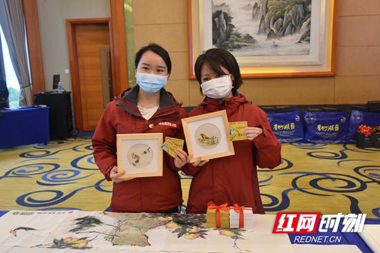 　两位湖南支援湖北医疗队队员展示湖南省文化馆赠送的“致敬战疫英雄”免费观演卡。