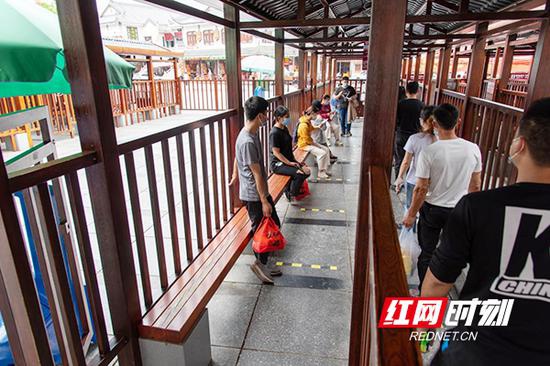 在南岳区游客服务中心,游客排队保持1.5米安全距离,等待工作人员“放行”。