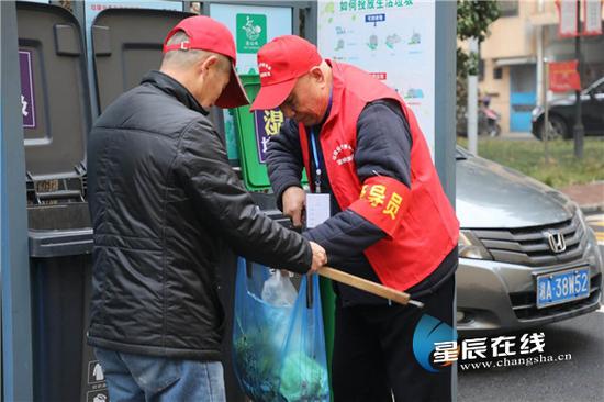 (督导员在垃圾分类点督导居民正确进行垃圾分类。龙旭 摄)