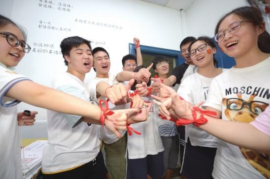  （7 月 6 日，安博长沙同升湖实验学校，考生信心满满地展示手上的红丝带。组图 / 记者吴琳红杨旭）