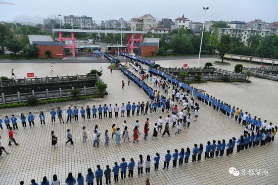  花垣县民族中学师生站成“V”字，为前往边城高级中学考点的考生加油送行。 龙恩泽 摄