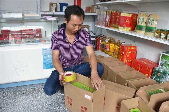 桂东县四都镇东水村快递站,站长钟建根正在打包黄桃将通过快递发往全国各地。