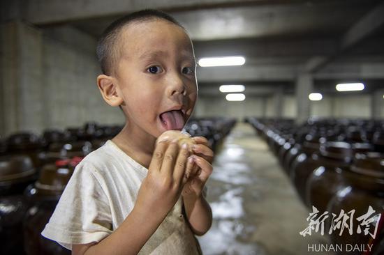 (8月21日,永州市冷水滩区麦子园村,小孩子舔吃陶土坛里腌制出来的大蒜。 湖南日报·华声在线记者 辜鹏博 摄)