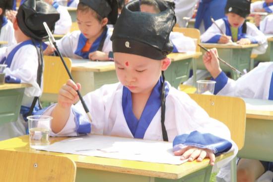 △ 8 月 31 日,长沙雨花区砂子塘吉联小学,参加 “ 开笔礼 ” 的一年级新生正在用毛笔。图 / 受访者提供