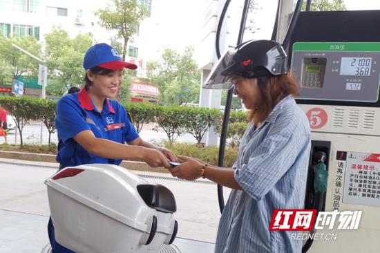 加油站工作人员对需要给摩托车加油的居民杨艳的证件进行检查。